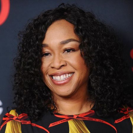 Shonda Rhimes in a black dress poses for a picture.